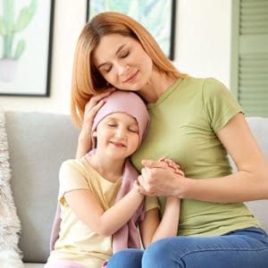 Menina paciente de câncer com a mãe em casa